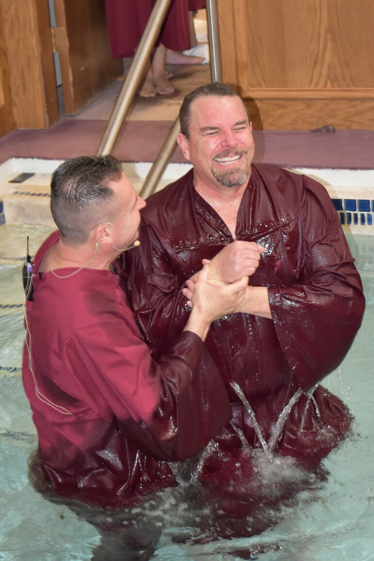 Man smiles while being baptized.